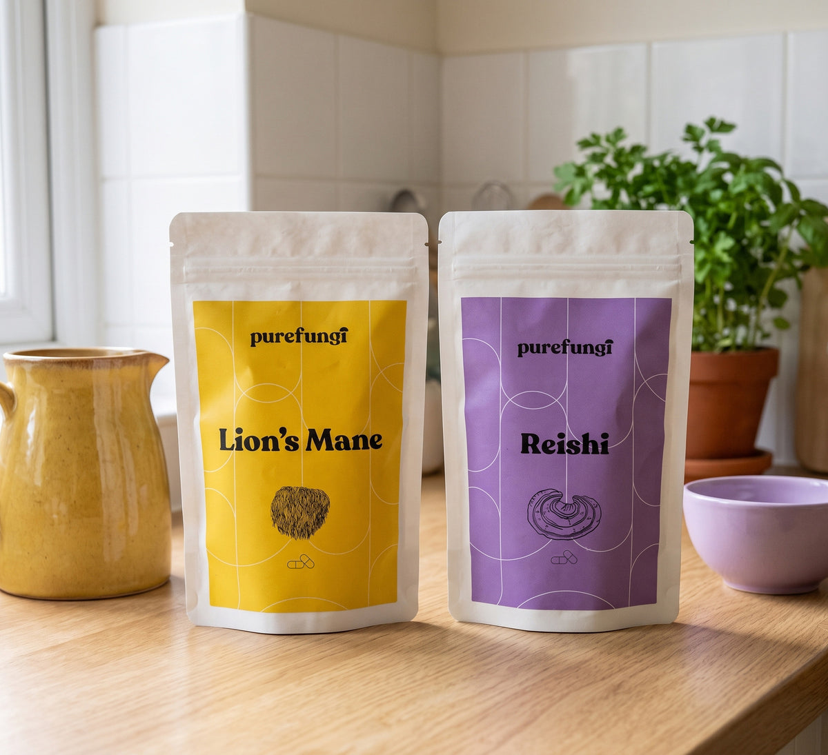 Pure Fungi Lion's Mane and Reishi capsules pouches standing on a kitchen worktop beside a yellow jug and a lilac bowl